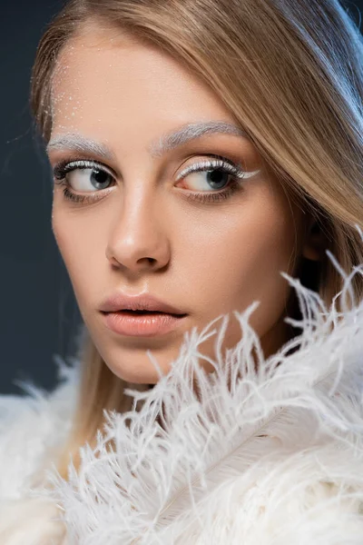 Portrait of pretty young woman looking away while posing near white feather isolated on blue — Stock Photo