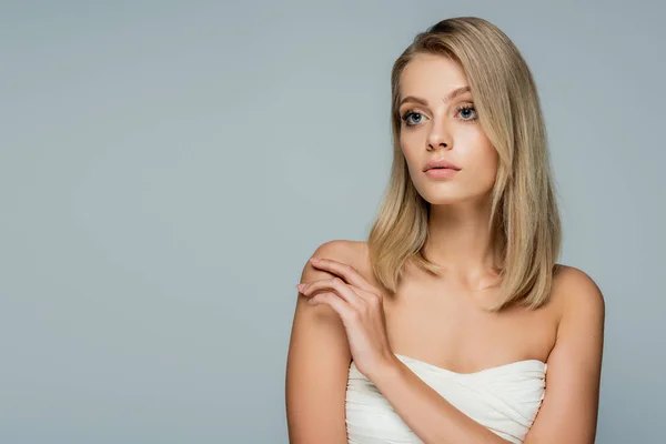 Blonde woman with bare shoulders and natural makeup looking away isolated on grey — Stock Photo