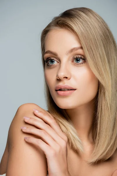 Retrato de mujer bonita con ojos azules y maquillaje natural mirando hacia otro lado aislado en gris - foto de stock