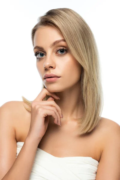 Retrato de mulher loira com olhos azuis olhando para a câmera ao tocar rosto isolado no branco — Fotografia de Stock