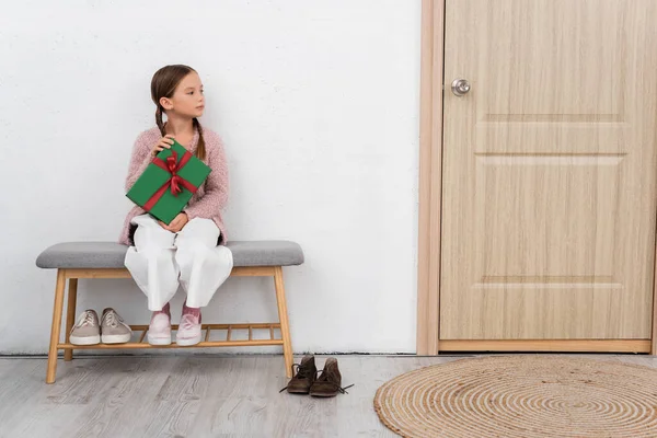 Preteen menina segurando presente perto da porta em casa — Fotografia de Stock
