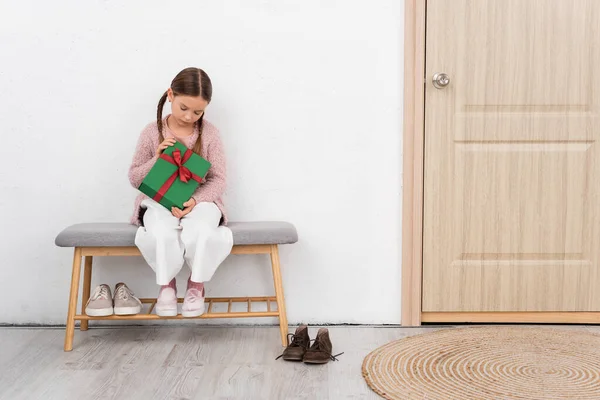 Preteen Kind hält Geschenk in der Nähe der Tür zu Hause — Stockfoto