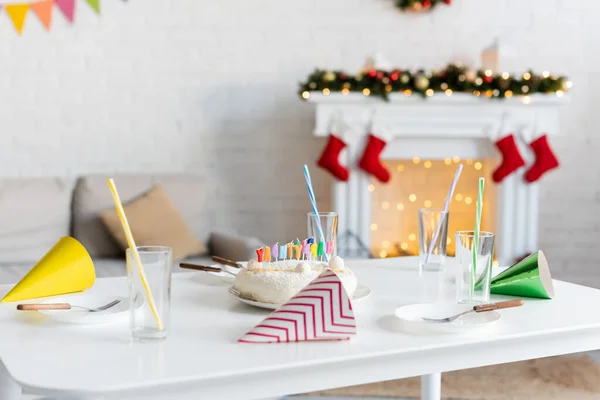 Chapeaux de fête et verres près du gâteau d'anniversaire sur la table à la maison — Photo de stock