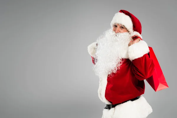 Babbo Natale barbuto in costume in possesso di shopping bag isolato su grigio — Foto stock