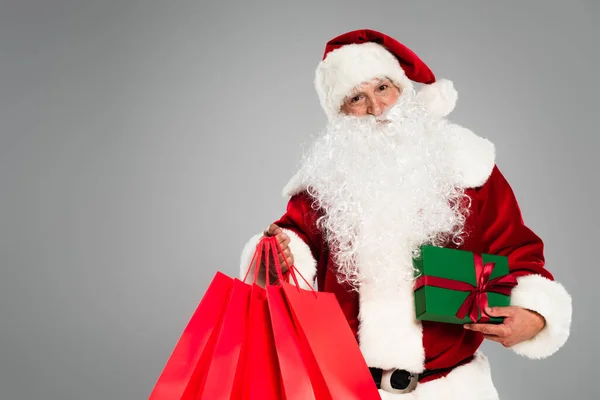 Babbo Natale in possesso di regali e borse della spesa isolati su grigio — Foto stock
