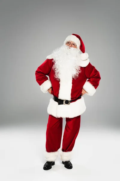 Pensive santa claus in costume looking away on grey background — Stock Photo