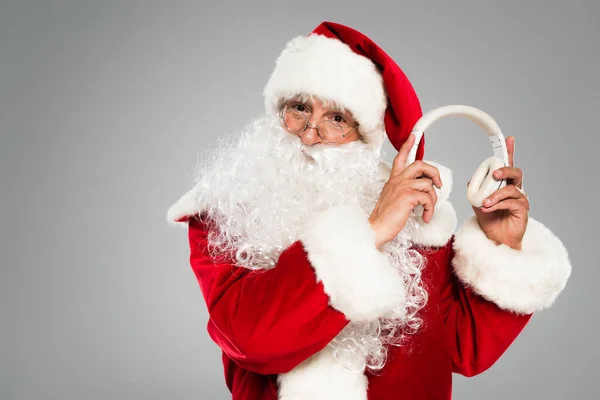 Santa claus in eyeglasses holding headphones isolated on grey — Stock Photo