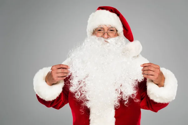 Санта-Клаус в окулярах і капелюсі дивиться на камеру ізольовано на сірому — стокове фото
