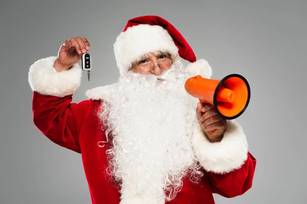 Father christmas holding loudspeaker and car key isolated on grey — Stock Photo