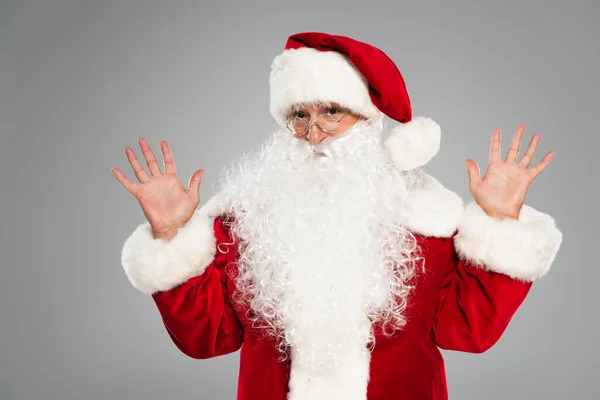 Santa Claus en gafas y traje agitando las manos aisladas en gris - foto de stock