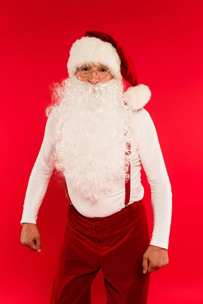 Санта-Клаус в окулярах дивиться на камеру ізольовано на червоному — стокове фото