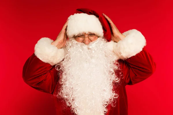 Père Noël dans des lunettes touchant la tête sur fond rouge — Photo de stock