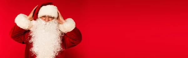 Бородатий Санта Клаус в окулярах торкається голови на червоному тлі з копіювальним простором, банер — стокове фото