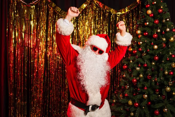 Pai natal em óculos de sol dançando durante a festa perto de pinheiros e ouropel — Fotografia de Stock