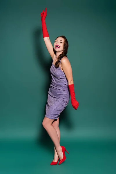 Comprimento total de encantadora jovem mulher em vestido roxo e luvas rindo em verde — Fotografia de Stock