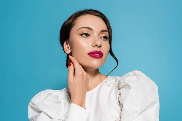 Encantadora joven con maquillaje mirando hacia otro lado aislado en azul - foto de stock