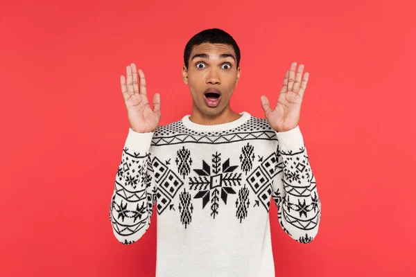 Shocked african american man in knitted sweater standing with open mouth and showing wow gesture isolated on red — Stock Photo