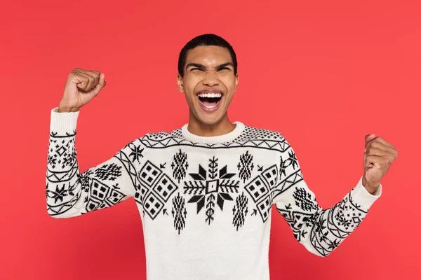 Felice uomo afroamericano con gli occhi chiusi mostrando gesto trionfale e gridando isolato sul rosso — Foto stock