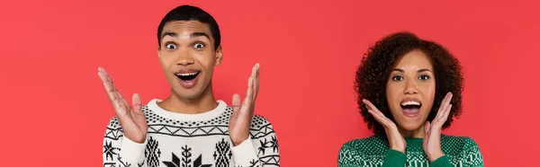 Astonished african american couple showing wow gesture while looking at camera isolated on red, banner — Stock Photo