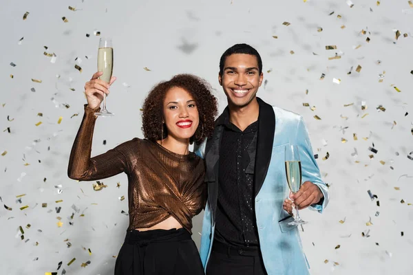 Элегантная африканская американка тост с шампанским рядом с счастливым парнем на сером фоне — стоковое фото