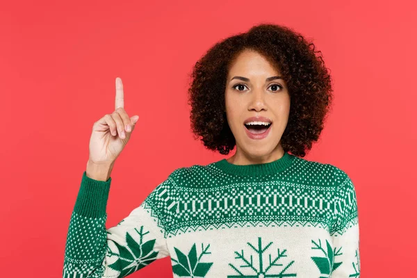 Excited african american woman in winter sweater with winter ornament showing idea gesture isolated on red — Stock Photo