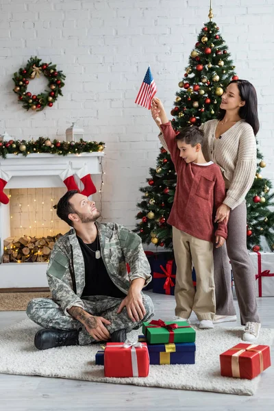 Patriotique garçon tenant Etats-Unis drapeau près sourire mère et père en uniforme militaire — Photo de stock