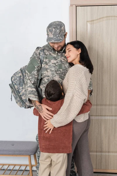 Felice madre e figlio che abbracciano l'uomo in uniforme militare tornando a casa — Foto stock