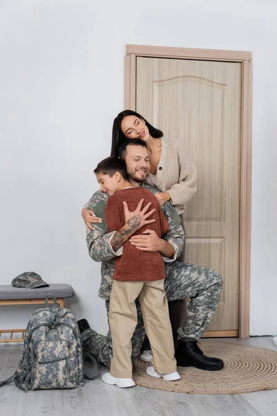 Famille heureuse étreignant homme militaire heureux de retour à la maison — Photo de stock