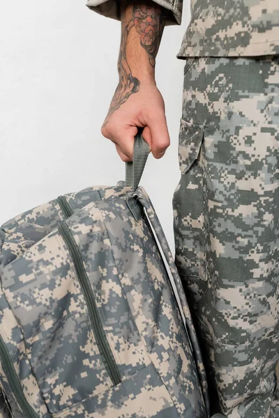 Cropped view of tattooed man in military uniform standing with backpack — Stock Photo