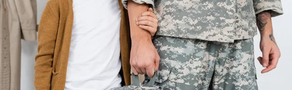 Partial view of boy holding hand of father in camouflage while meeting him at home, banner — Stock Photo