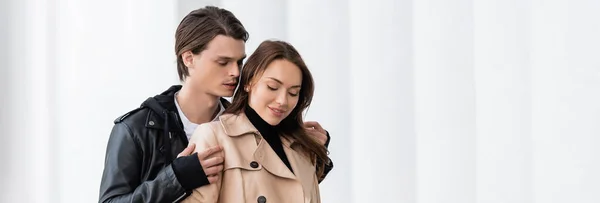 Homem elegante na jaqueta abraçando ombros de namorada feliz no casaco de trincheira, banner — Fotografia de Stock