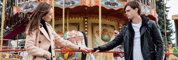 Junges Paar steht neben Karussell und berührt Hände im Vergnügungspark, Banner — Stockfoto