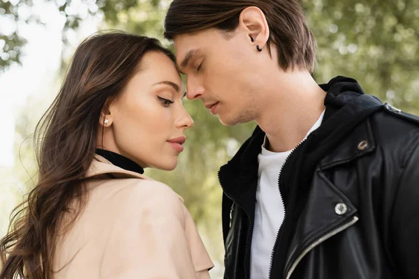 Side view of young man and pretty woman in trench coat during date outdoors — Stock Photo