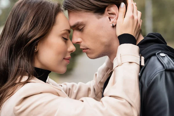 Side view of smiling woman in beige trench coat hugging boyfriend — Stock Photo