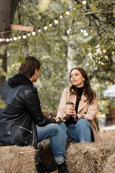 Giovane e bella donna con tazza di carta che si tiene per mano con il fidanzato nel parco autunnale — Foto stock