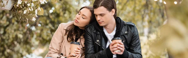 Young woman with closed eyes holding paper cup and leaning on shoulder of boyfriend, banner — Stock Photo