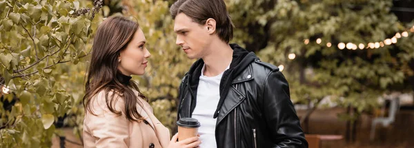 Seitenansicht einer jungen Frau und eines jungen Mannes in stylischen Outfits, die sich im Park anschauen, Banner — Stockfoto