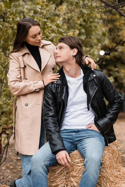 Morena mujer en gabardina abrazando elegante novio en el parque otoñal - foto de stock