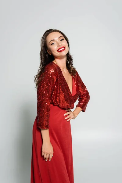 Весела жінка в сукні і з червоними губами позує на сірому фоні — стокове фото