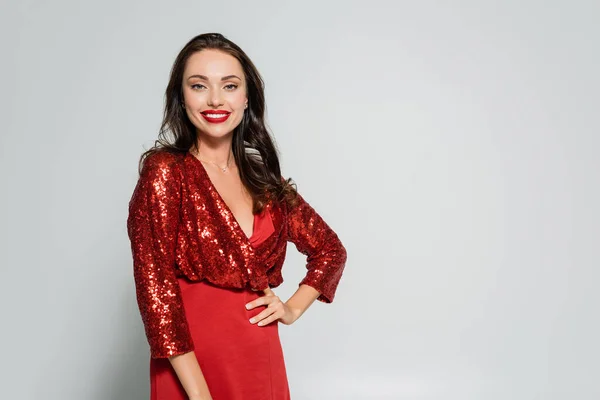 Stilvolle Frau im eleganten roten Kleid blickt in die Kamera auf grauem Hintergrund — Stockfoto
