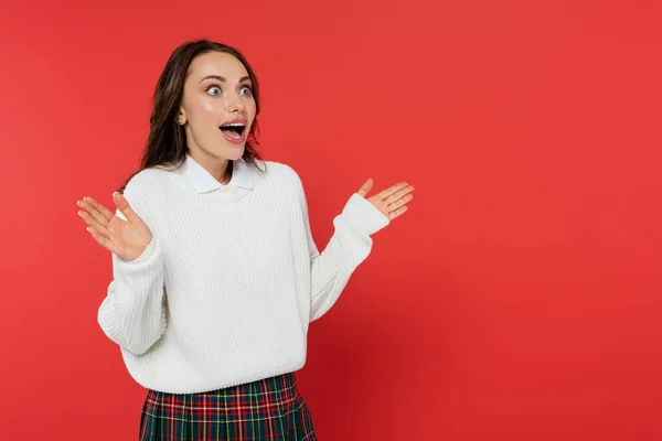 Femme choquée en pull chaud regardant loin isolé sur rouge — Photo de stock