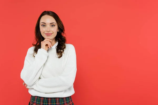 Lächelnde brünette Frau im weißen Pullover blickt vereinzelt in die Kamera auf Rot — Stockfoto