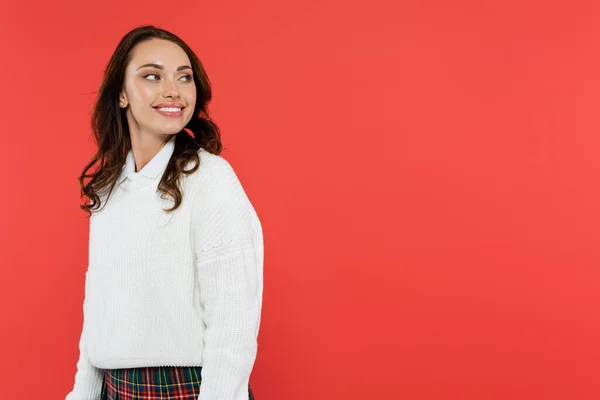 Donna sorridente in maglione bianco guardando lontano isolato sul rosso — Foto stock