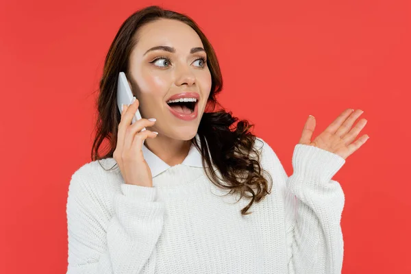 Erstaunte Frau in weißem Pullover spricht auf Handy isoliert auf rot — Stockfoto