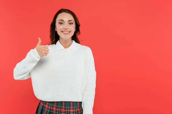 Young woman in cozy jumper showing like gesture isolated on red — Stock Photo