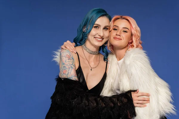 Felici amici queer in bianco e nero giacche di eco pelliccia sorridenti alla fotocamera isolata su blu — Foto stock