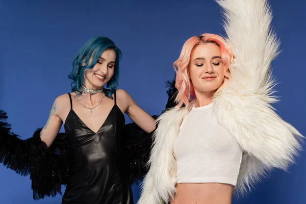 Happy queer friends in trendy clothes dancing at christmas party isolated on blue — Stock Photo