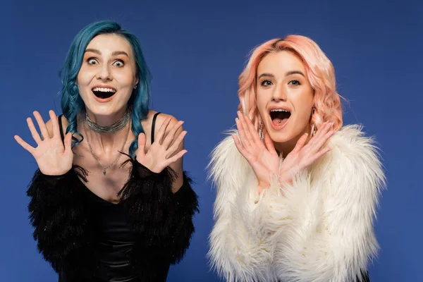 Astonished nonbinary friends showing wow gesture and looking at camera isolated on blue — Stock Photo