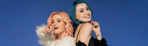 Stylish and happy nonbinary friends looking at camera and posing isolated on blue, banner — Stock Photo