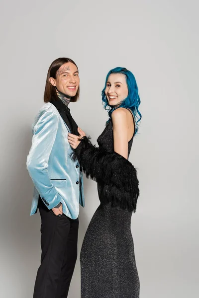 Persona queer in parrucca blu vicino tatuato amico non binario in elegante blazer su sfondo grigio — Foto stock